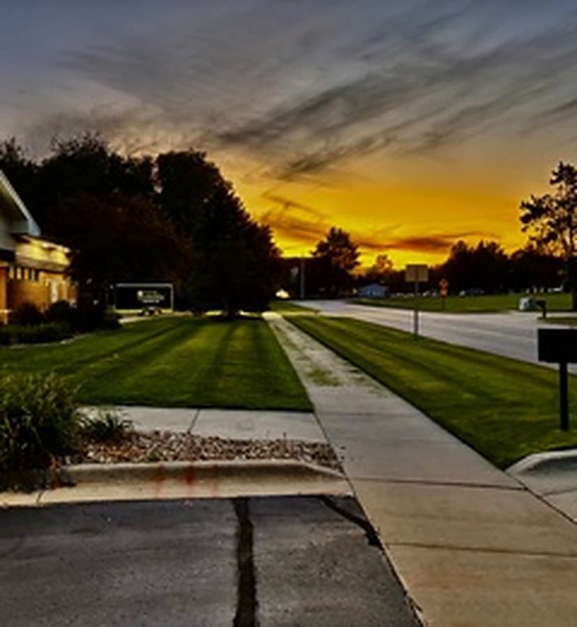 Commercial lawn and walkway at sunset with an orange sky
